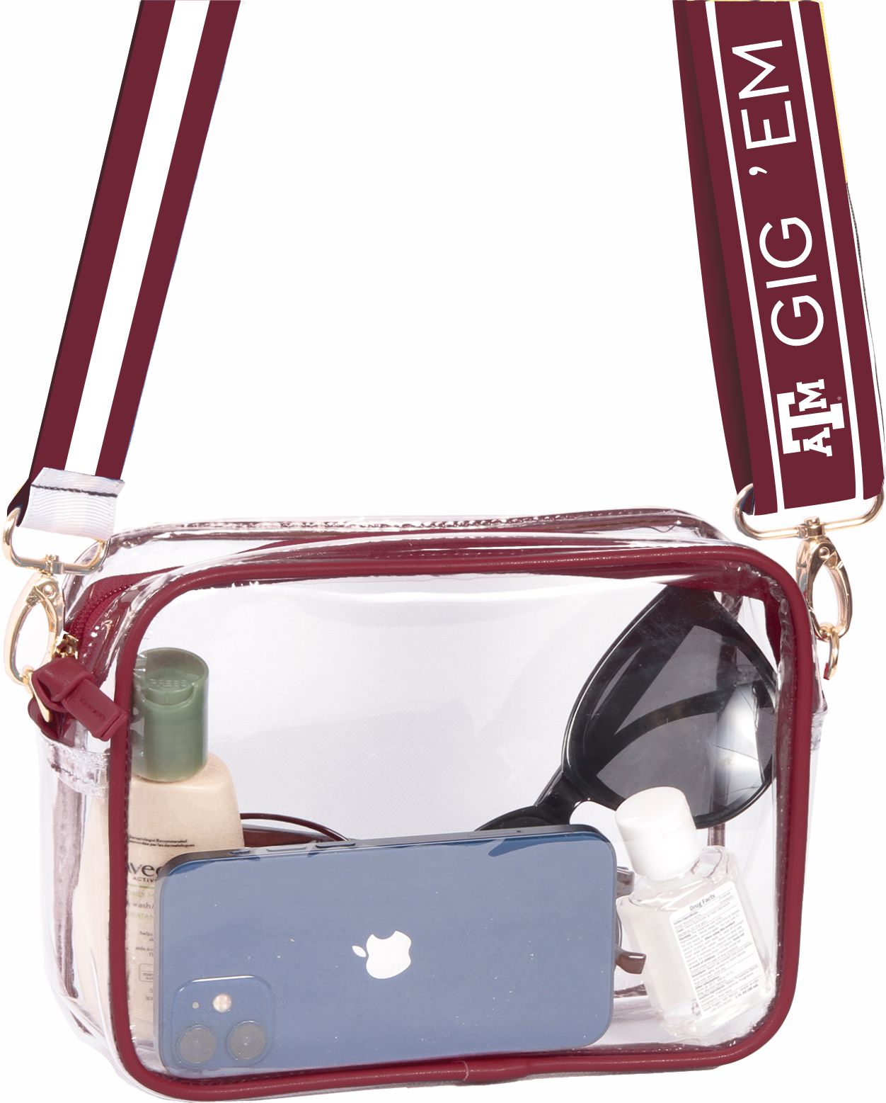 A clear vinyl purse with red vegan leather accents and brass hardware. It features a shoulder strap and is shown with a smartphone, sunglasses, and a bottle inside.