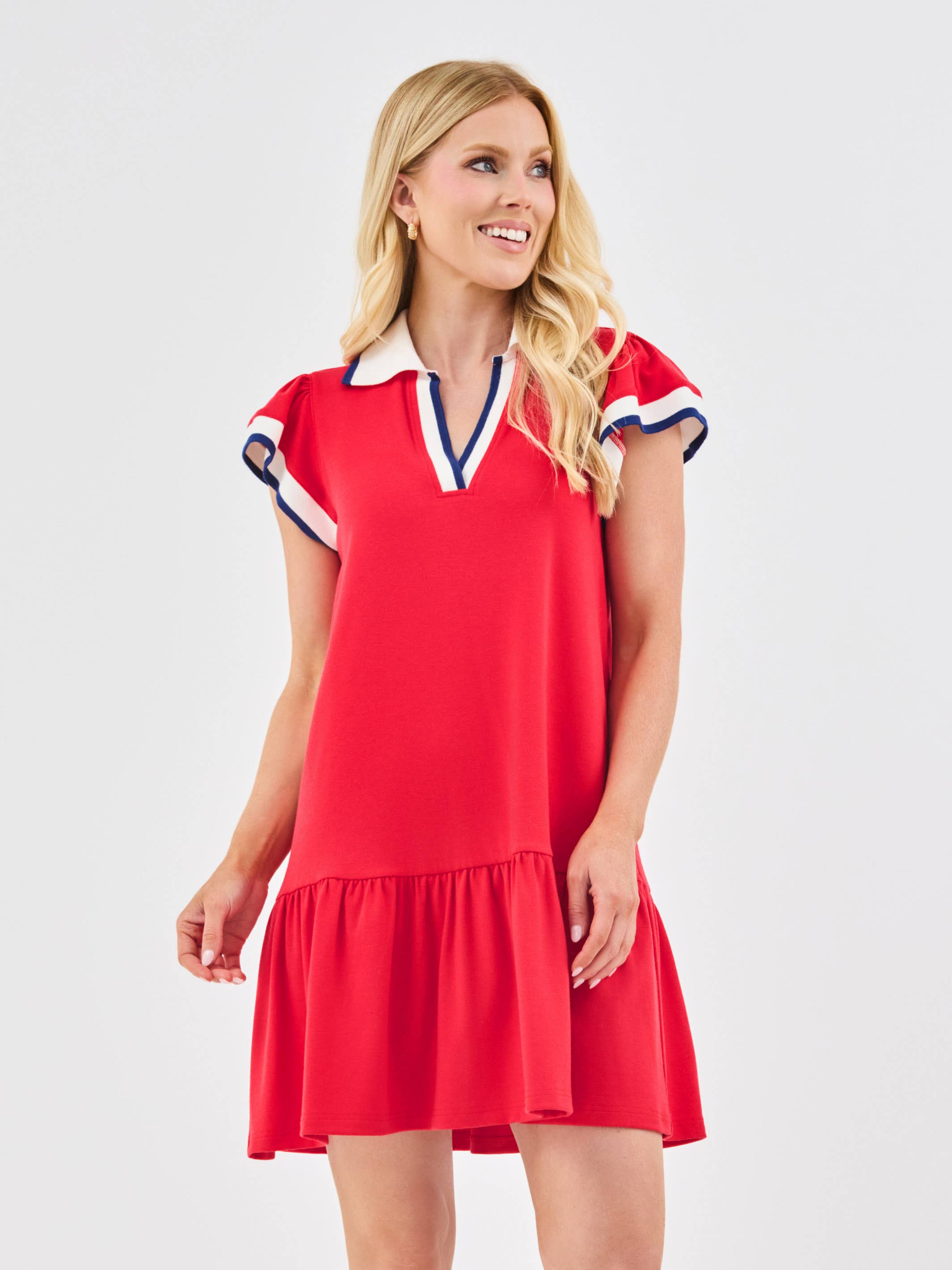 Woman wearing a red dress with white collar and blue trim on a light gray background