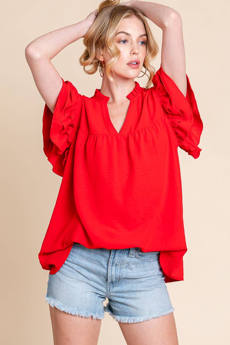 Woman wearing a red blouse and denim shorts on a beige background